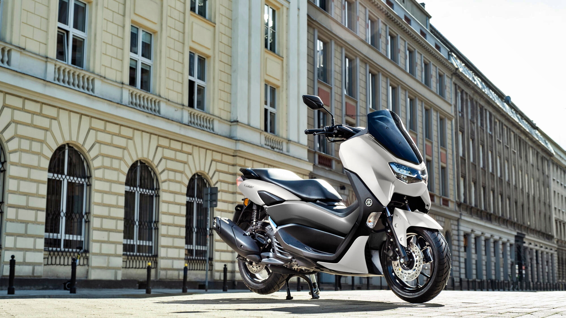 Vista lateral Yamaha NMAX 125 en ambiente urbano, destacando su diseño compacto.