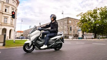 Vista lateral del Yamaha NMAX 125 en ambiente urbano, destacando su diseño compacto.