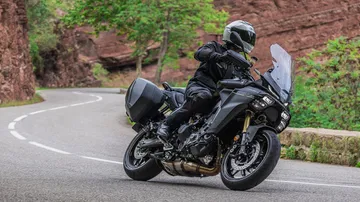 Vista dinámica de la Yamaha Tracer 9 en curva demostrando su agilidad.