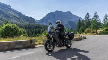 Crossover Yamaha Tracer 9 en carretera con paisaje montañoso de fondo.