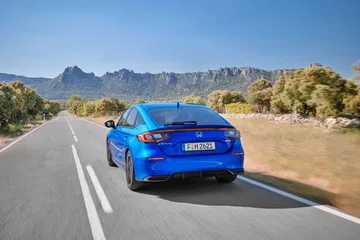 Vista lateral y trasera del Honda Civic 2024 en un entorno natural.