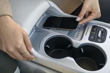 Espacio funcional del consola central con soporte para dispositivos y portavasos.