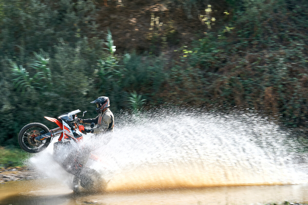 Imagen de una KTM sobre terreno acuático, mostrando su rendimiento en situaciones extremas.