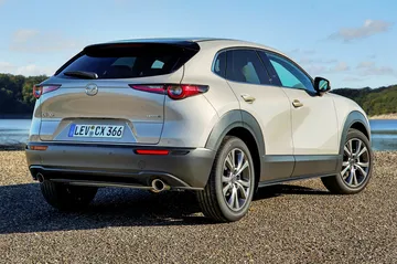 Vista trasera y lateral del Mazda CX-30, destacando su dise&ntilde;o elegante y moderno.