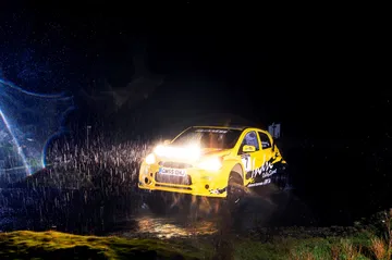 Vista dinámica del Mitsubishi Mirage R5 en acción durante la noche, destacando su rendimiento en rally.