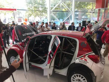 Vista lateral del Mitsubishi Mirage R5 en exposición, competición de rally.