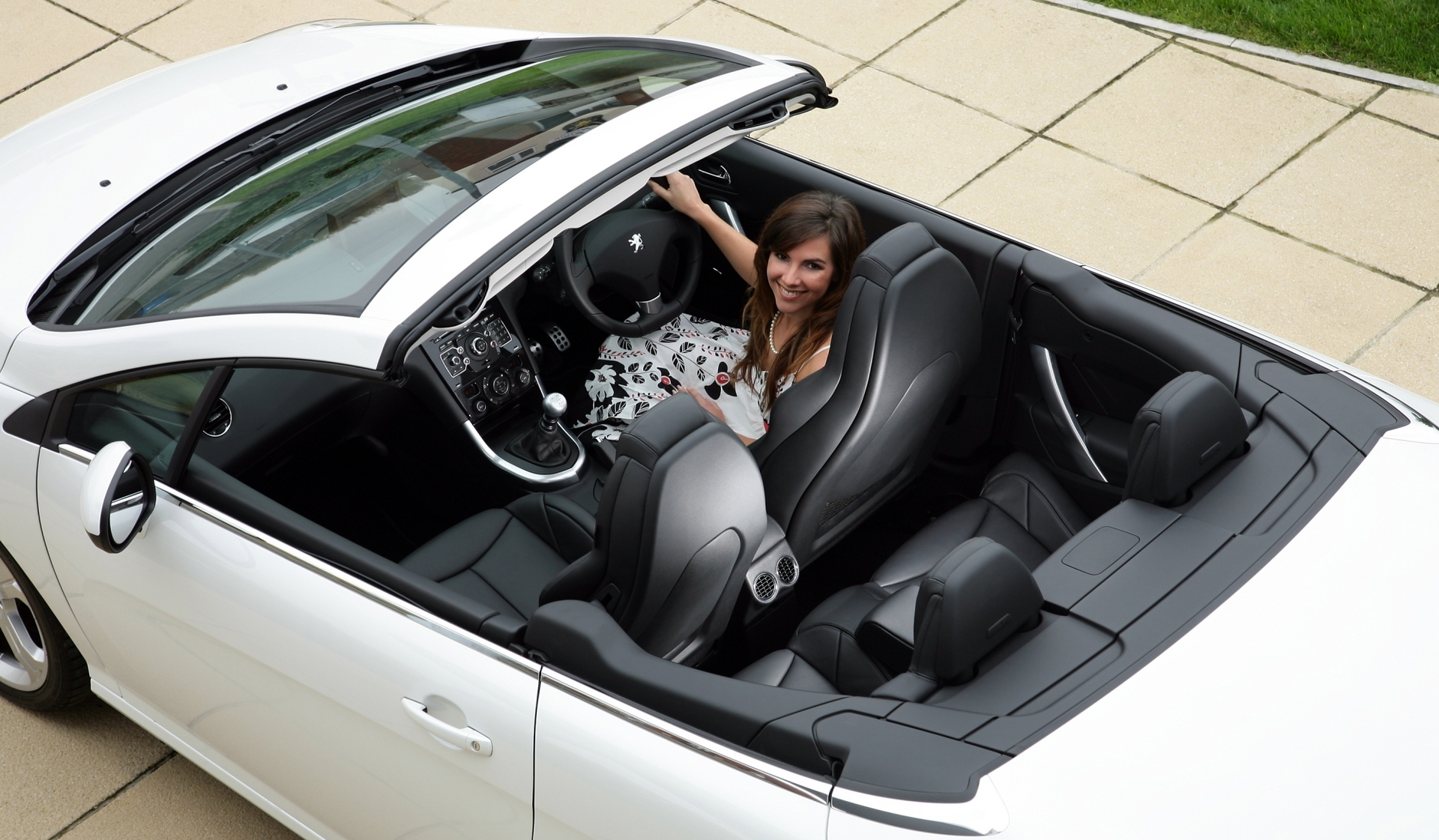 Vista lateral del Peugeot 308 CC con capota abierta, ideal para disfrutar del aire libre.