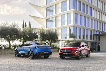 Dos Renault Rafale E-Tech 4x4, uno azul otro rojo, junto a edificio moderno