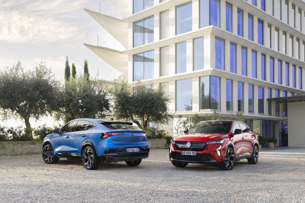Dos Renault Rafale E-Tech 4x4, uno azul otro rojo, junto a edificio moderno