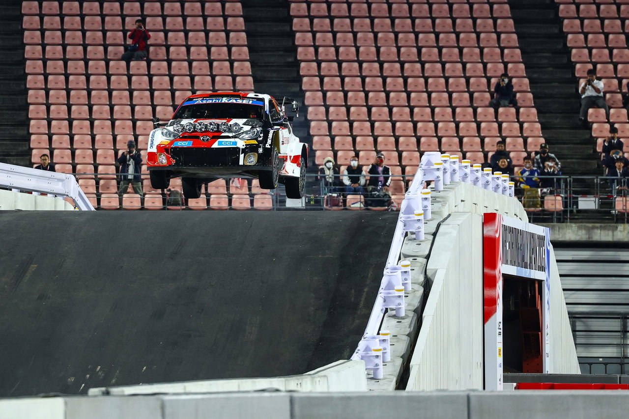 Un coche de rally tomándose un salto impresionante en Japón, mostrando su agilidad.