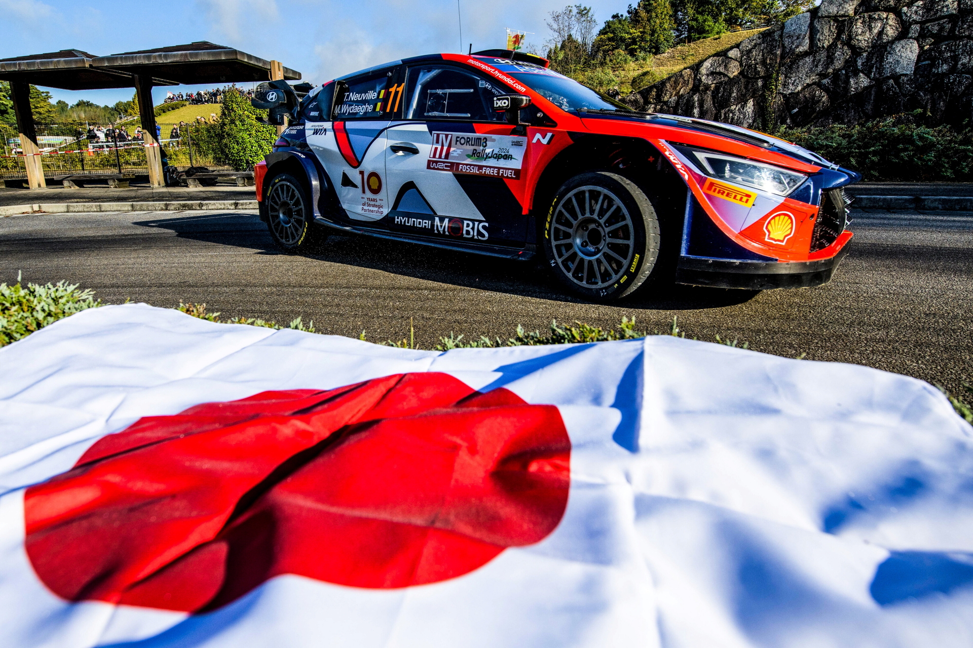 Vehículo en acción con bandera de Japón, simbolizando su regreso.