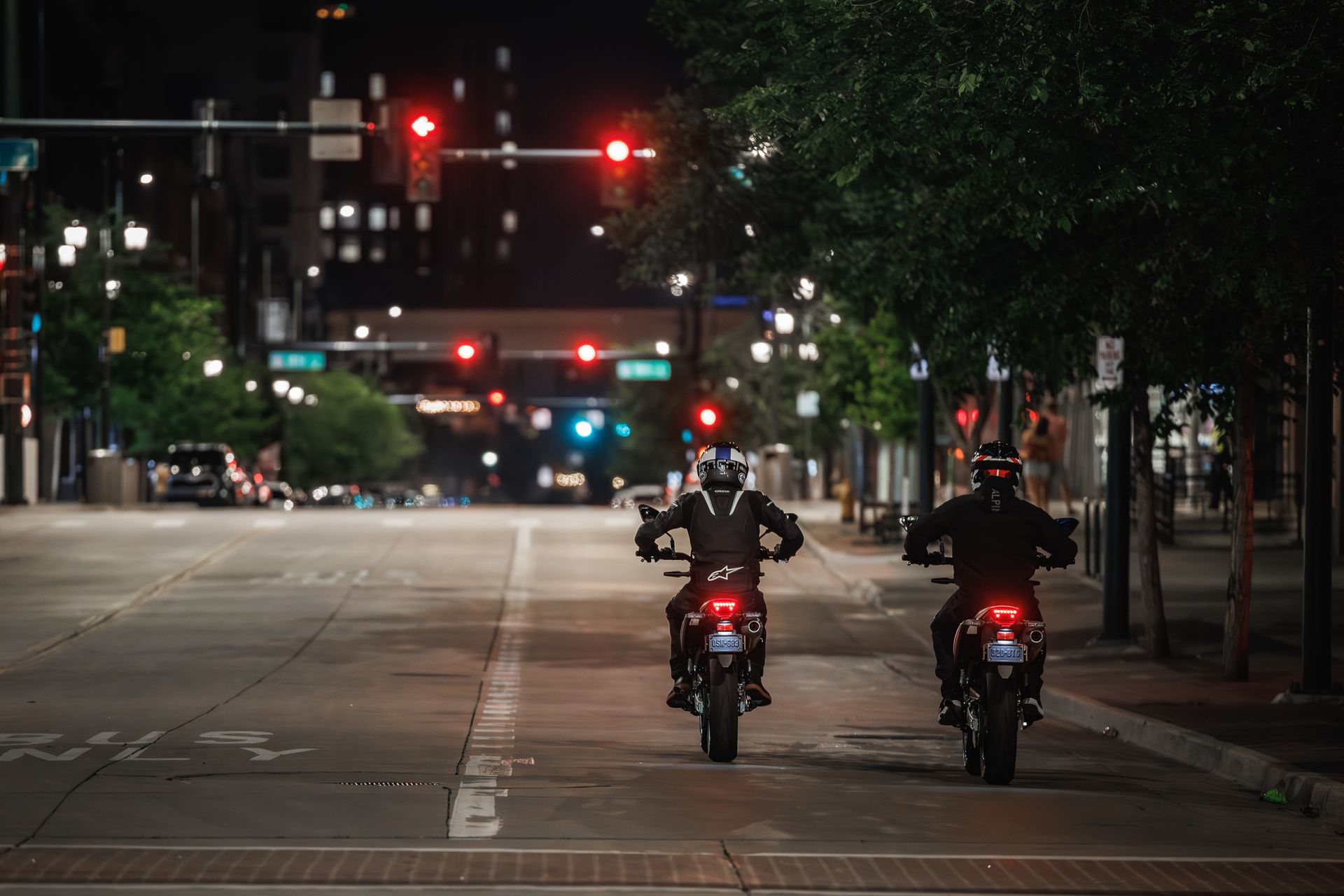 Dos motos Suzuki DR-Z4SM iluminadas por semáforos en una ciudad vacía.