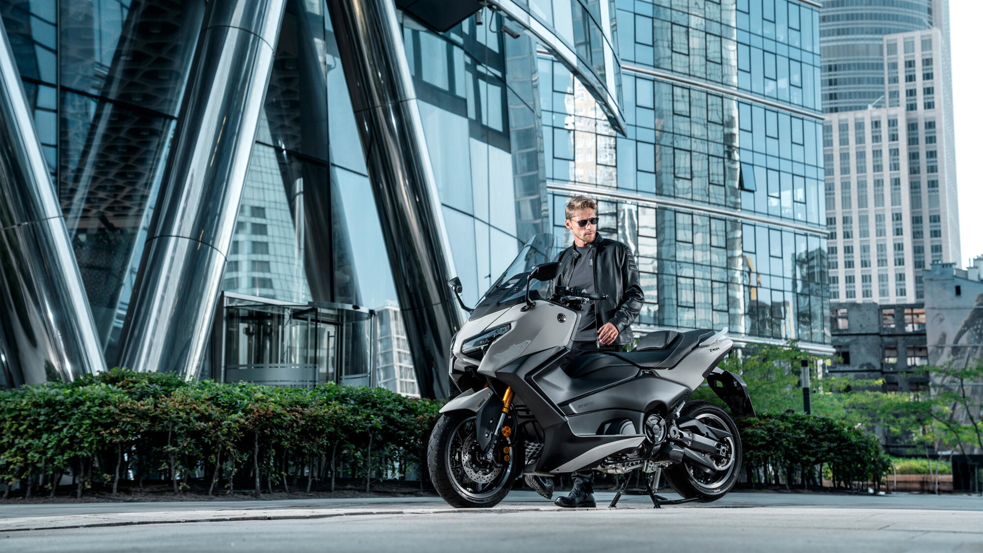 La Yamaha TMAX 2025 se muestra en un entorno urbano, destacando su diseño lateral
