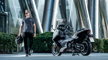 La Yamaha TMAX 2025 Tech Max reluce en su hábitat urbano, promesa de agilidad y estilo.