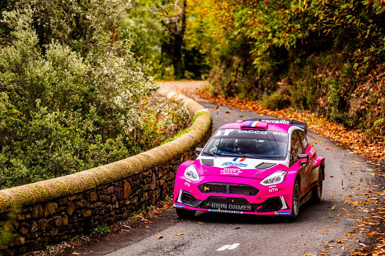 El coche de Iron Dames muestra un diseño vibrante y agresivo en plena acción. 