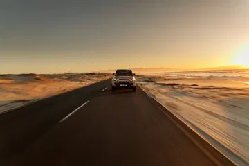 El Defender Octa se desliza por una carretera en un entorno pintoresco, mostrando su robustez.