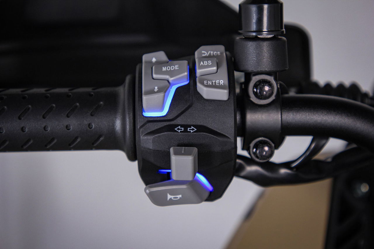 Detalle del puño del manillar con controles modernos y diseño ergonómico.