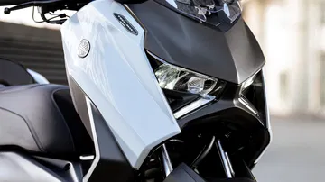 Detalle del faro y panel frontal de la Yamaha XMAX 2025, que destaca por su diseño agresivo.