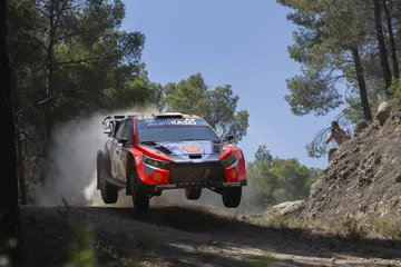 Coche de rally en acción, saltando sobre una pista, mostrando su diseño aerodinámico.