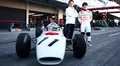 Yuki Tsunoda posando junto a un histórico monoplaza de Honda en el circuito.