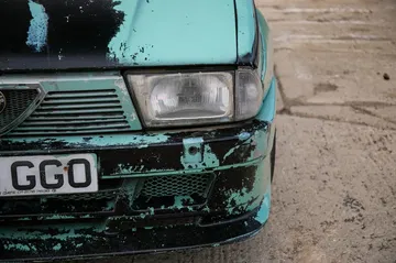 Vista frontal del Alfa Romeo 75, mostrando desgaste y carácter de coleccionista