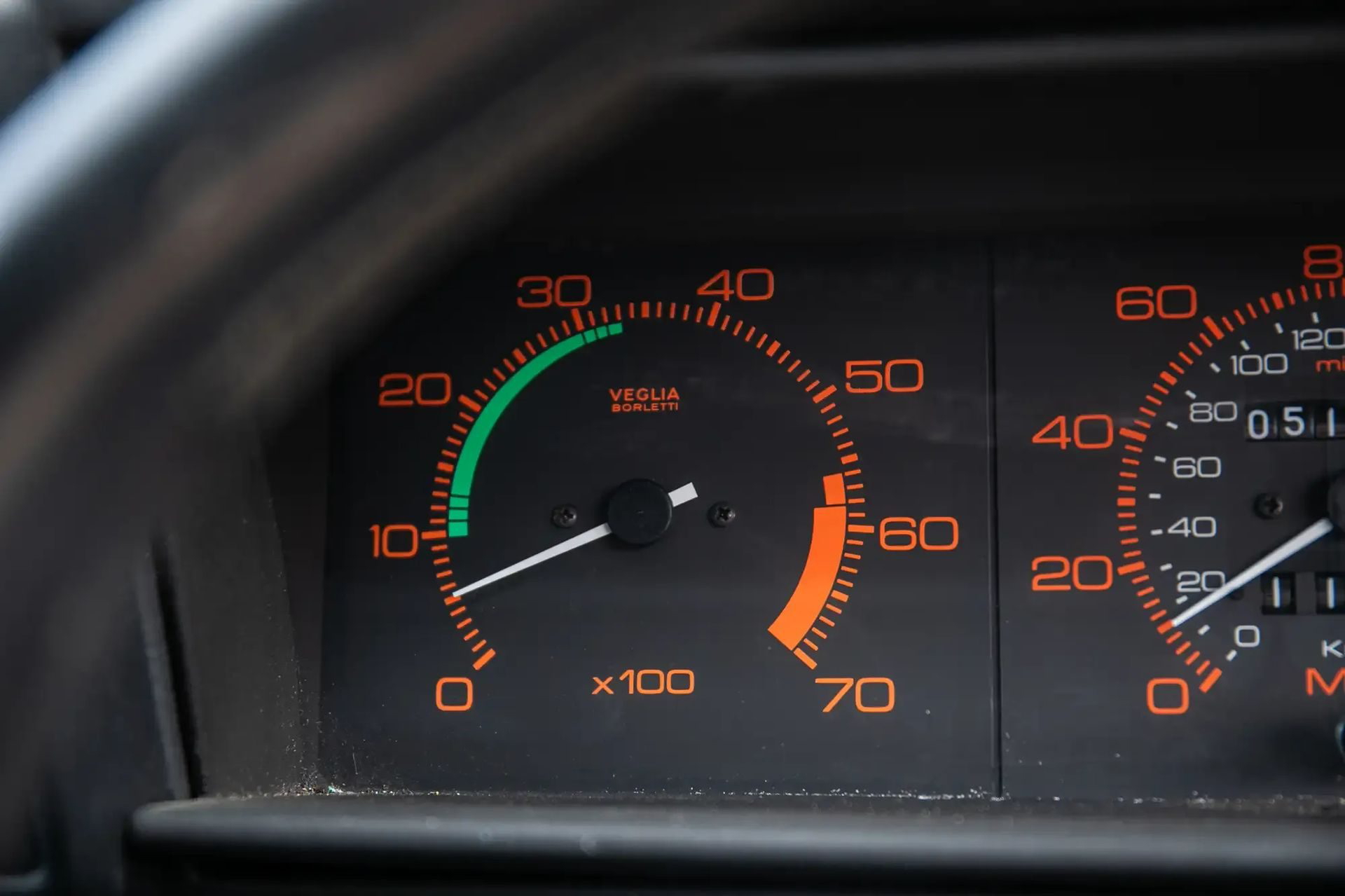 Detalle del cuadro de instrumentos del Alfa Romeo 75, mostrando los indicadores de velocidad y revoluciones.