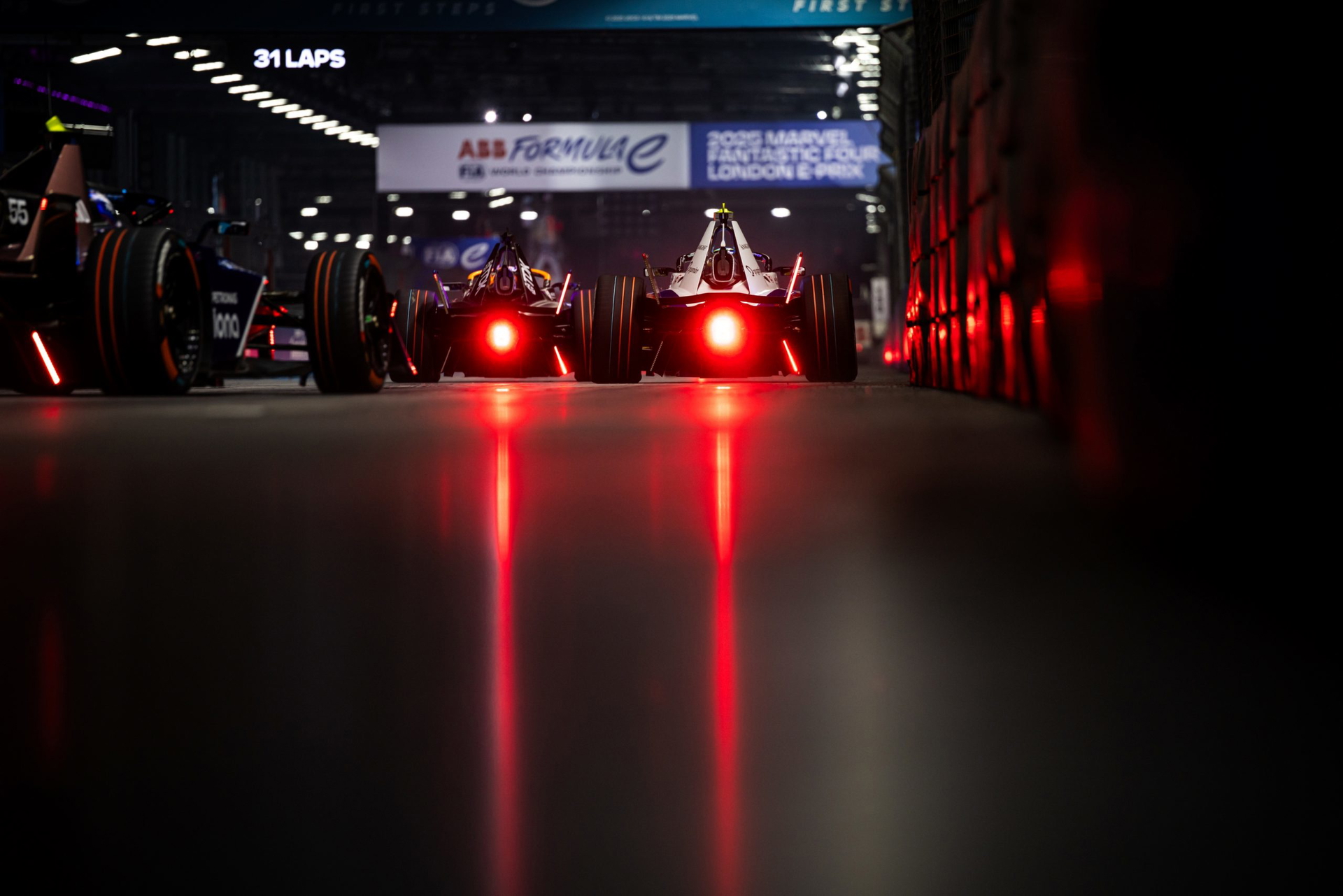 Dos monoplazas eléctricos listos para la carrera en Londres, con luces traseras iluminadas.