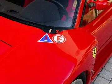 Detalle del Ferrari F40 LM, mostrando su emblemático color rojo y logotipos distintivos.