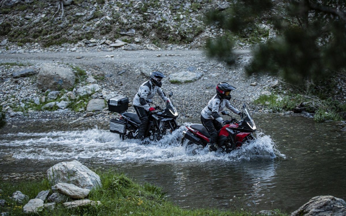 Dos motocicletas Macbor Montana XR1 EVO cruzando un río, resaltando su capacidad off-road.