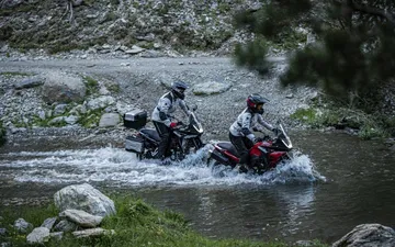 Dos motocicletas Macbor Montana XR1 EVO cruzando un arroyo en un entorno montañoso.