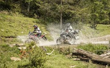 Dos motociclistas cruzando un charco, mostrando la versatilidad de la Macbor Montana XR1 EVO en terrenos difíciles.