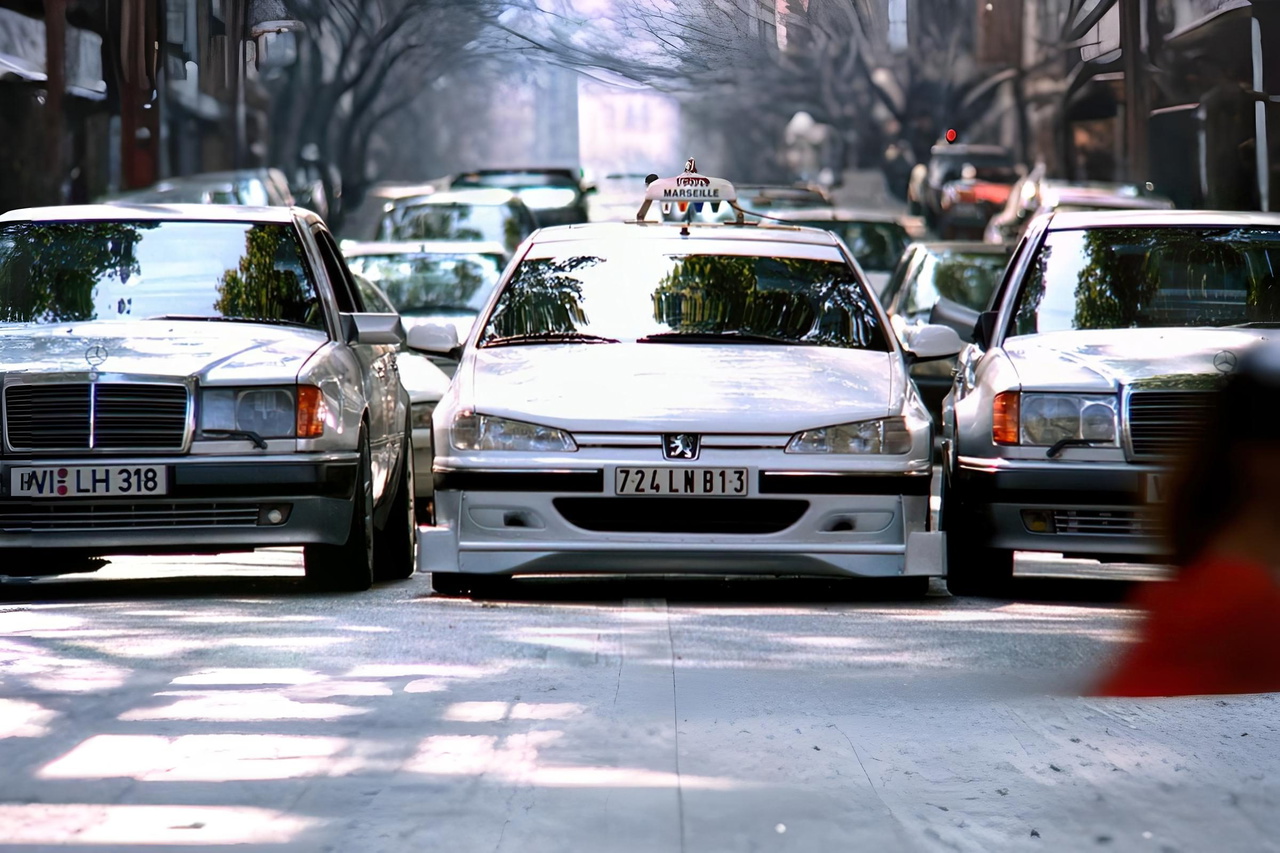 Mercedes y un taxi se enfrentan en un entorno urbano, mostrando contrastes de diseño.