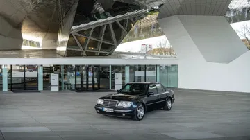 Un elegante Mercedes-Benz destaca en un entorno arquitectónico moderno.