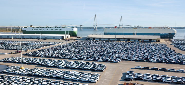Vista aérea de un puerto de automóviles europeo con vehículos listos para exportación.