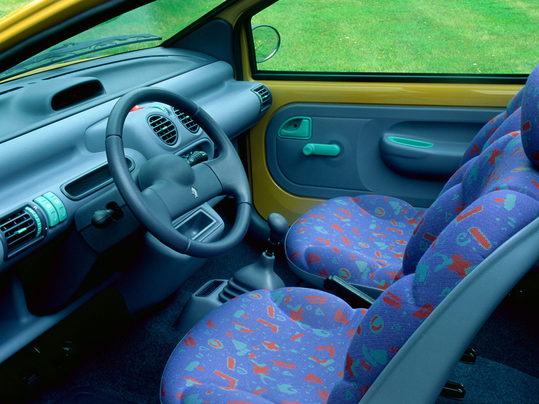 Vista del interior del Renault Twingo clásico, mostrando el diseño colorido de los asientos y el tablero.