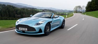 Vista dinámica del Aston Martin DB12 Volante en carretera, destacando su diseño y aerodinámica.