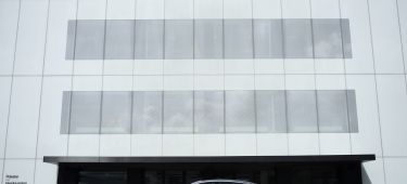 Vista lateral del Polestar enfrente de edificio corporativo, destacando su diseño aerodinámico.