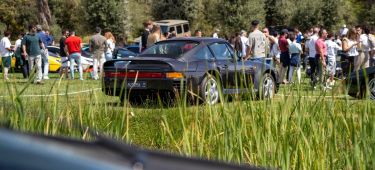 Clásico Porsche 911 en exhibición rodeado de entusiastas del motor.