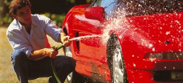 Imagen de Ayrton Senna lavando un Honda NSX rojo, destacando la figura del deportivo.