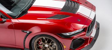 Ángulo agresivo que muestra la parte delantera y lateral de un coche deportivo rojo.