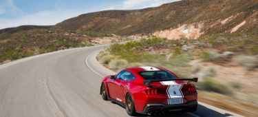 Imponente vista trasera y lateral de un coche deportivo rojo en movimiento, destacando su diseño aerodinámico y alerón.