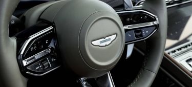 Detalle del volante del Aston Martin con vistas a su emblema sobresaliente y comandos de control.